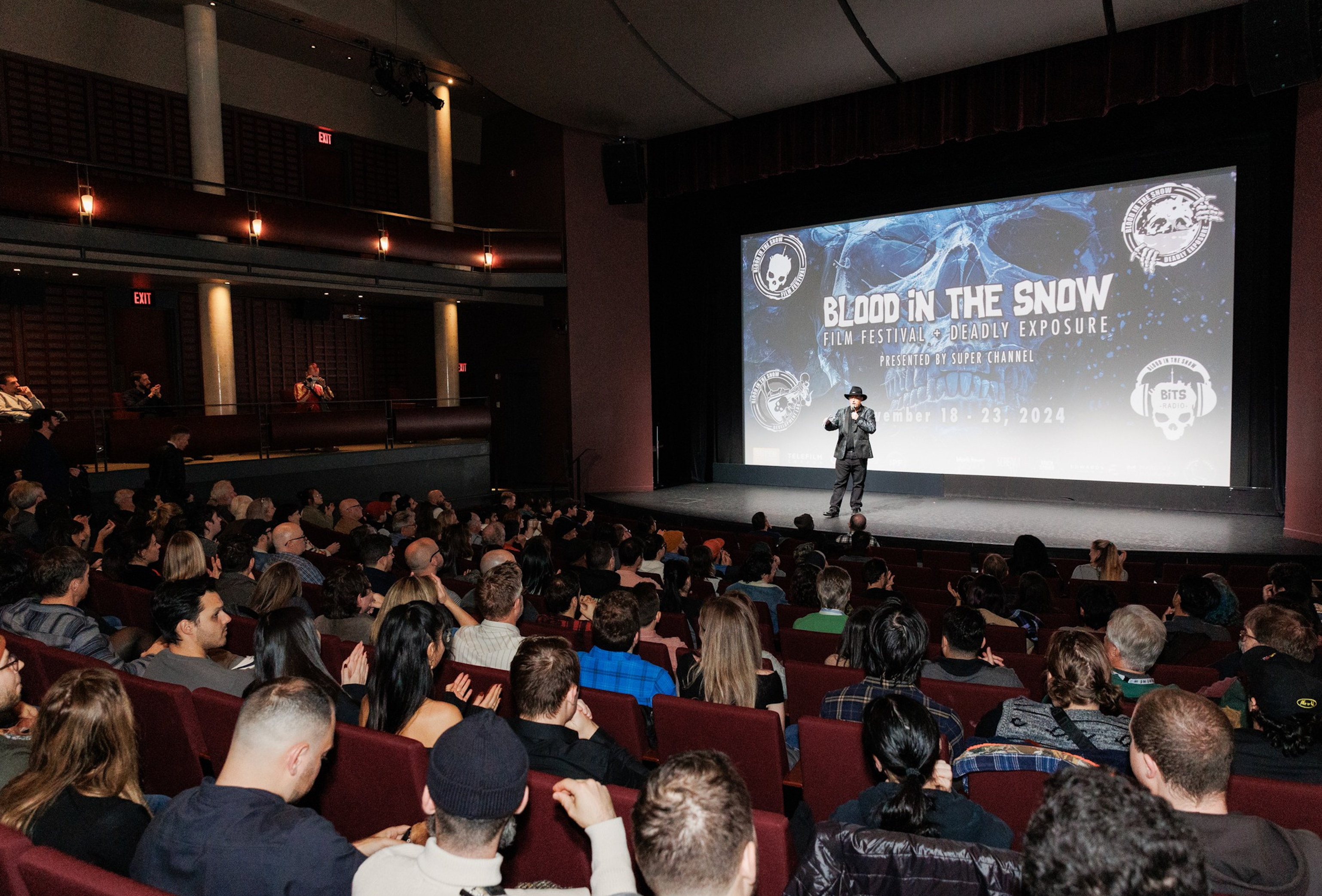 Photograph of Festival Director Kelly Michael Stewart on stage at the theatre announcing a screening